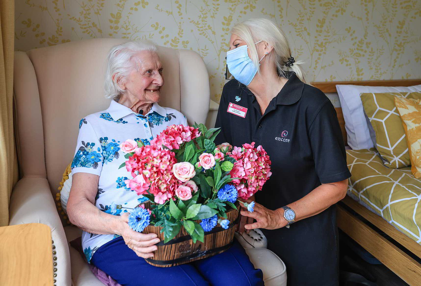 Encore resident holding flowers while smiling at carer