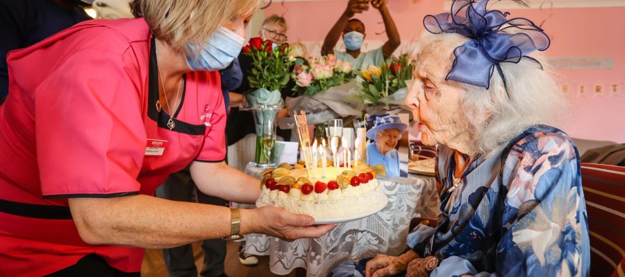Fairmile Grange resident blowing out candles on her birthday cake for her 100th birthday